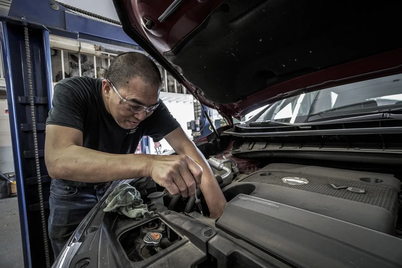 Mechanic working under the open hood of a car